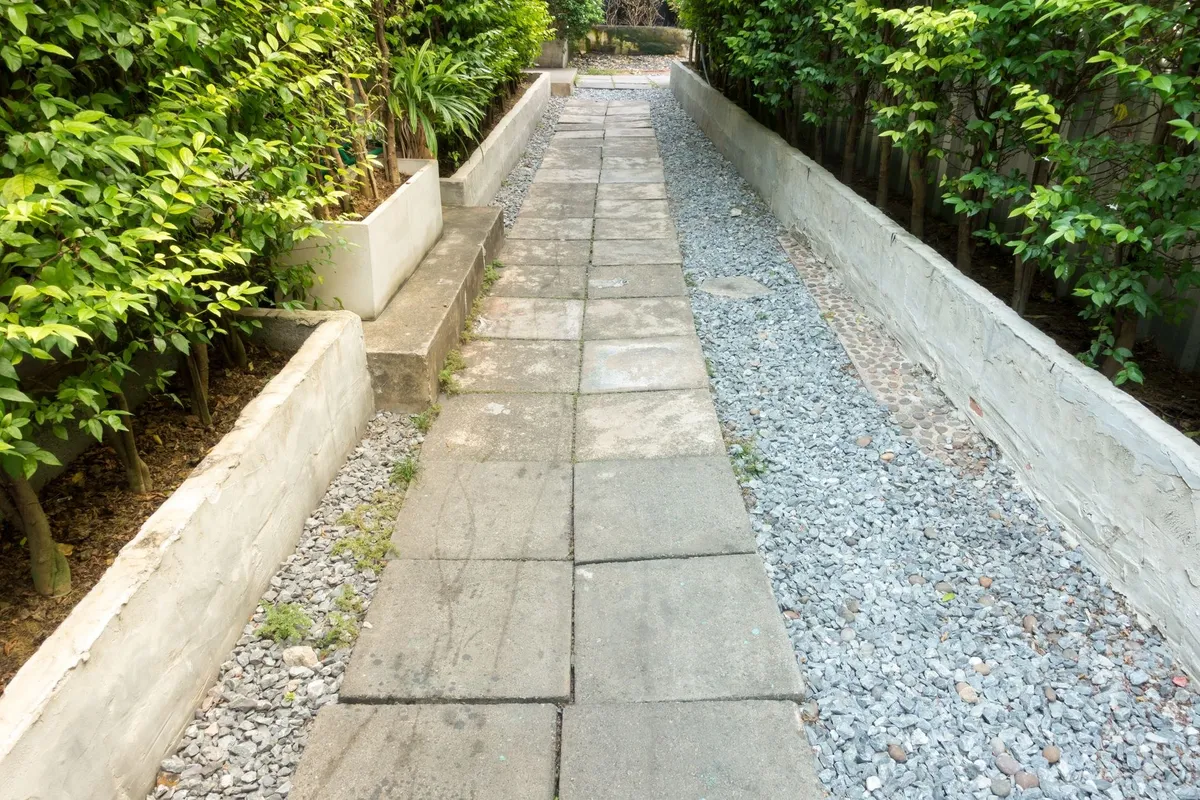 Exploring Creative Paver Designs for Your Venice, FL Outdoor Space 2 A serene garden path with vibrant green plants and a pebbled walkway, showcasing creative outdoor design.